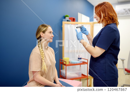 A woman at an appointment with a neurologist. A doctor examining young female patient using neurological hammer to test reflexes. A woman at an appointment with a neurologist. A doctor examining young female patient using neurological hammer to test reflexes. 120467867