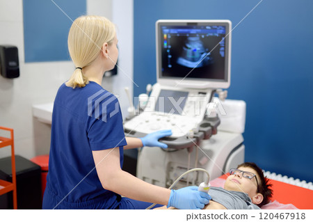 Doctor making abdominal ultrasound for boy using scanner machine. Doc runs ultrasound sensor over patient tummy looking at screen. Medical examination of internal organs for school kids Doctor making abdominal ultrasound for boy using scanner machine. Doc runs ultrasound sensor over patient tummy looking at screen. Medical examination of internal organs for school kids 120467918
