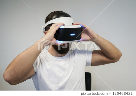 Close up of man wearing VR headset, exploring virtual worlds with blue LED lighting 120468421