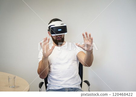 Man using hand gestures to interact with virtual environment while wearing VR headset 120468422