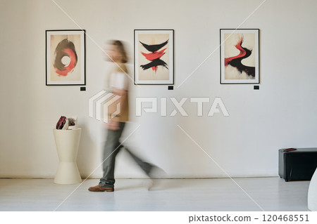 Blurred figure walking through art gallery exhibiting abstract paintings on wall demonstrating motion. Artwork showcasing dynamic brushstrokes and vivid contrasts Blurred figure walking through art gallery exhibiting abstract paintings on wall demonstrating motion. Artwork showcasing dynamic brushstrokes and vivid contrasts 120468551