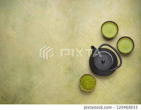 Matcha tea powder and hot drink in bowls with black iron teapot on green background, Japanese tea top view Matcha tea powder and hot drink in bowls with black iron teapot on green background, Japanese tea top view 120468633