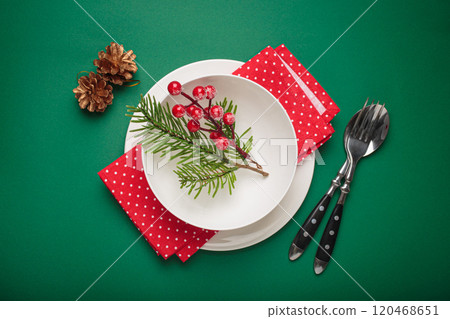 Christmas table setting decorated with fir branches and holly berries on green background 120468651