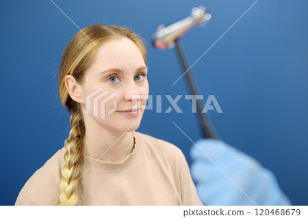 A woman at an appointment with a neurologist. A doctor examining young female patient using neurological hammer to test reflexes. A woman at an appointment with a neurologist. A doctor examining young female patient using neurological hammer to test reflexes. 120468679