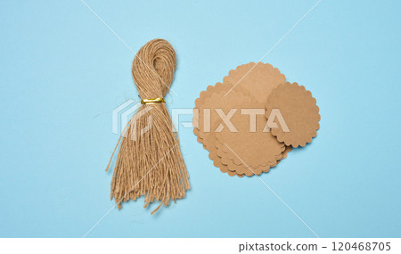 Bundle of brown rope and round paper tags on blue background, top view Bundle of brown rope and round paper tags on blue background, top view 120468705
