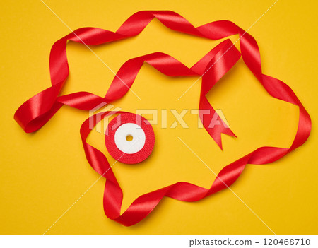 Spool of red silk ribbon on yellow background, top view 120468710