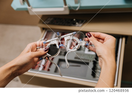 Hands holding trial lenses for precision eye exams and vision correction in optometry clinic 120468936