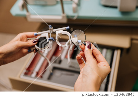 Hands selecting lens for trial glasses in a modern optometry clinic for vision correction Hands selecting lens for trial glasses in a modern optometry clinic for vision correction 120468945