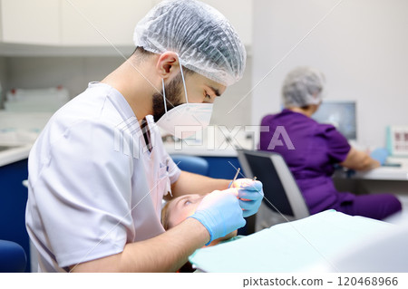 Dentist and patient at modern medical center. Doctor treats a young woman teeth in hospital. Practitioner examines the patient before orthodontists or prosthetics treatment. 120468966