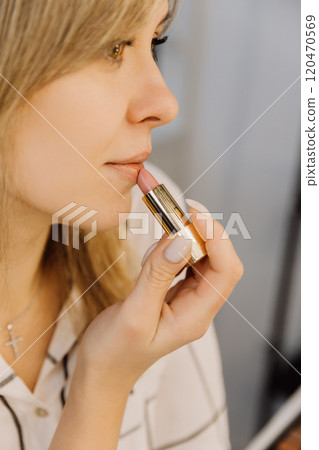 Close up of a woman applying nude lipstick for a natural and elegant makeup look Close up of a woman applying nude lipstick for a natural and elegant makeup look 120470569