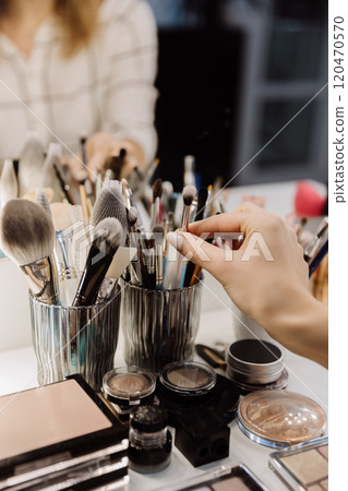 Hand selecting a makeup brush from a collection of beauty tools for a flawless application 120470570