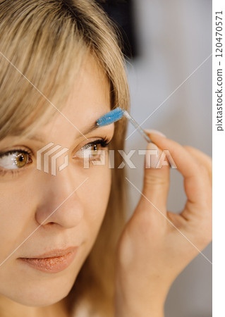 Close up of eyebrow grooming with blue spoolie brush for flawless beauty and defined brows 120470571