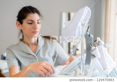 Cosmetologist using modern HydraFacial machine in 120470863