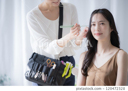A makeup artist and model preparing for hair and makeup 120472328