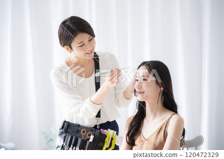 A makeup artist and model preparing for hair and makeup A makeup artist and model preparing for hair and makeup 120472329