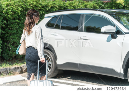 Back view of a businesswoman pulling a suitcase towards her car 120472684