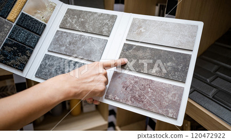 Designer hand pointing at stone tile sample on display catalog Designer hand pointing at stone tile sample on display catalog 120472922