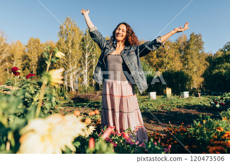 Woman celebrating the simple joys of rural life with open arms in her garden. Autumn day of contentment: Woman enjoying her garden and sustainable lifestyle Woman celebrating the simple joys of rural life with open arms in her garden. Autumn day of contentment: Woman enjoying her garden and sustainable lifestyle 120473506