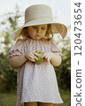 Joyful Girl in a Dress and Straw Hat, Holding an 120473654