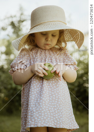 Joyful Girl in a Dress and Straw Hat, Holding an 120473654