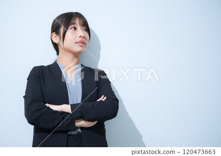 商業場景中,身穿西裝的年輕女子雙臂交叉,抬頭仰望,表情厚顏無恥,充滿挑戰精神。 商業場景中,身穿西裝的年輕女子雙臂交叉,抬頭仰望,表情厚顏無恥,充滿挑戰精神。 120473663