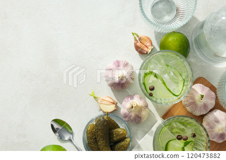 Brine cocktail with cucumber, bottle, lime and garlic on light background, space for text 120473882