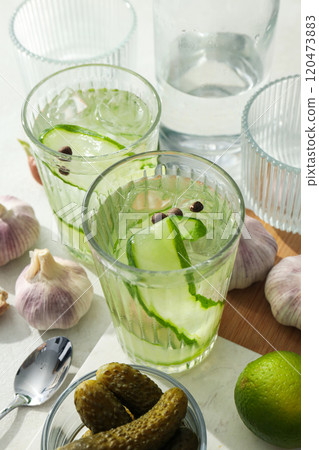 Brine cocktail with cucumber, bottle, lime and garlic on light background, close up Brine cocktail with cucumber, bottle, lime and garlic on light background, close up 120473883