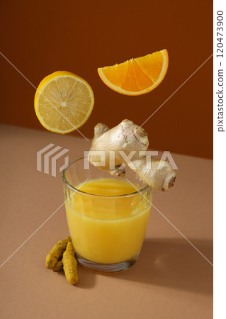 Glass with juice and falling ingredients on dark red background Glass with juice and falling ingredients on dark red background 120473900