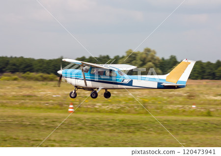 Small private airplane landing on the grass field 120473941