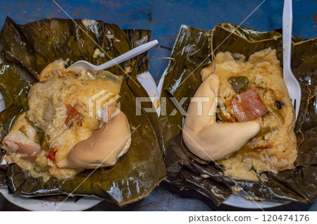 Two Nacatamales served in a banana leaf on the table. Top view of two traditional Nacatamales served on banana leaf, Two Nacatamales with bread served on the table, Venezuelan Hallaca served 120474176