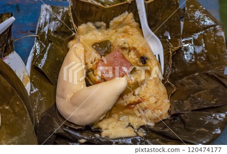 Nacatamal served with bread in a banana leaf on the table. Traditional Nacatamal served in banana leaf, Nicaraguan Nacatamal with bread on the table, Traditional Venezuelan Hallaca served 120474177
