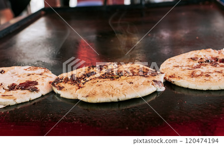 Three traditional Nicaraguan pupusas with melted grilled cheese, Traditional cheese pupusas on the grill, Close up of traditional handmade pupusas on the grill. Three traditional Nicaraguan pupusas with melted grilled cheese, Traditional cheese pupusas on the grill, Close up of traditional handmade pupusas on the grill. 120474194