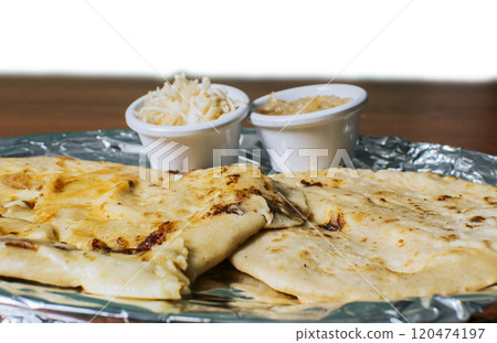 Close up of delicious Salvadoran pupusas with cheese served on the table. Traditional pupusas served with salad on the table. Two Nicaraguan pupusas with salad on the table Close up of delicious Salvadoran pupusas with cheese served on the table. Traditional pupusas served with salad on the table. Two Nicaraguan pupusas with salad on the table 120474197