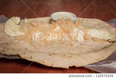 Close up of Nicaraguan Quesillo served on wooden table. Top view of Nicaraguan Quesillo served on wooden table. Traditional Nicaraguan Quesillo served on wooden table 120474209