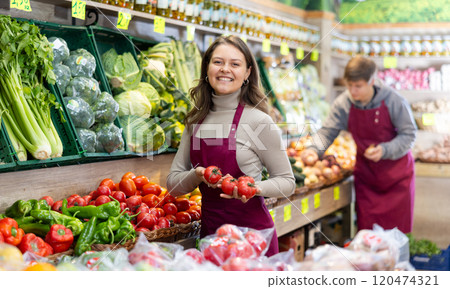 Young woman seller lays out tomatoes on counter 120474321