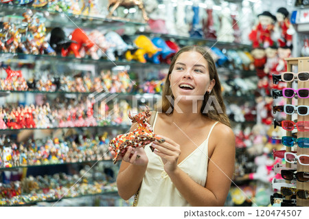 Female traveler buyer chooses ceramic ox, glass figurine of bull Female traveler buyer chooses ceramic ox, glass figurine of bull 120474507