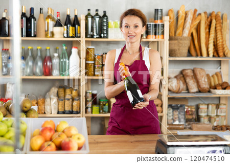 Adult woman seller offers wine in grocery store 120474510