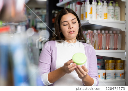 Surprised woman choosing hair care products at cosmetics store Surprised woman choosing hair care products at cosmetics store 120474573