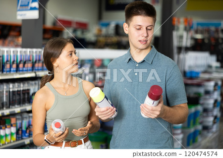 Positive couple choosing acrylic paint spray in building supermarket Positive couple choosing acrylic paint spray in building supermarket 120474574