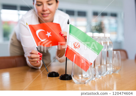 Little flag of Iran on table and flag of Turkey put next to it by young woman Little flag of Iran on table and flag of Turkey put next to it by young woman 120474604