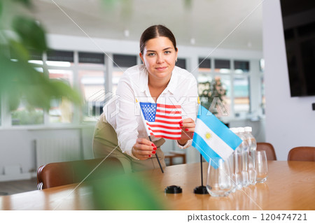 Employee of delegation prepares negotiating table - sets up flag of United States and Argentine 120474721