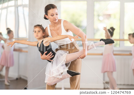 During training, teacher holds girl in arms and rehearses pair ballet dance. 120474769