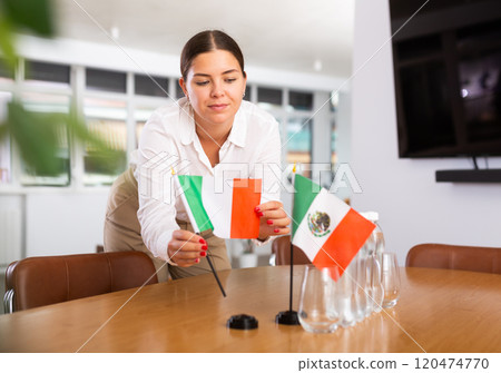Young lady sets miniatures flags of Mexico and Italy for international negotiations 120474770