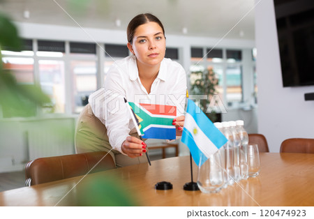 Young lady sets miniatures flags of Argentina and South Africa for international negotiations 120474923