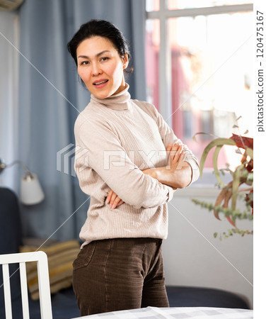 Positive woman posing at table at home Positive woman posing at table at home 120475167