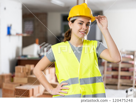 Woman builder posing on indoor construction site Woman builder posing on indoor construction site 120475248