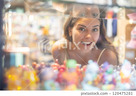 Traveler girl examines goods in glass shop window of souvenir shop 120475281