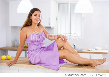 Sensual girl in nightie sitting on table in kitchen 120475295