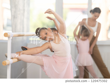 Girls dancers doing stretching at barre 120475302