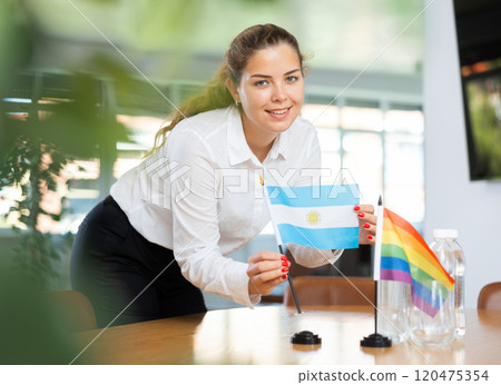 Young lady sets miniatures flags of LGBT and Argentina before international negotiations 120475354